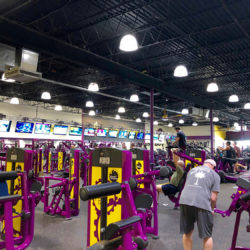 Image of a Planet Fitness interior, showing a large room filled with exercise and strength training equipment.